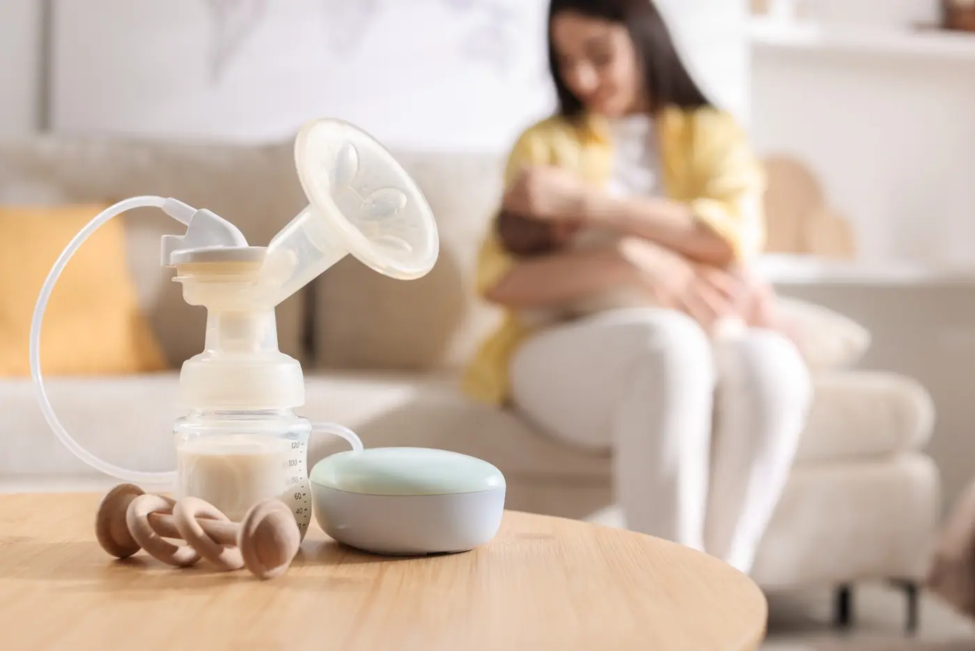 A breast pump ready for use while a mother holds her baby at home