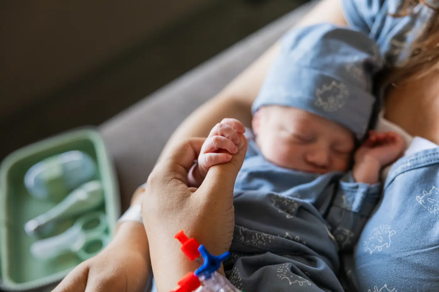 A newborn holding an adult’s finger