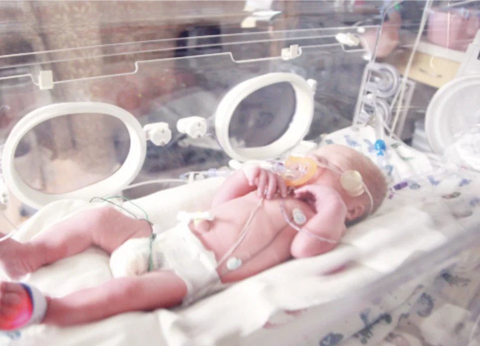 A premature baby resting in a hospital incubator