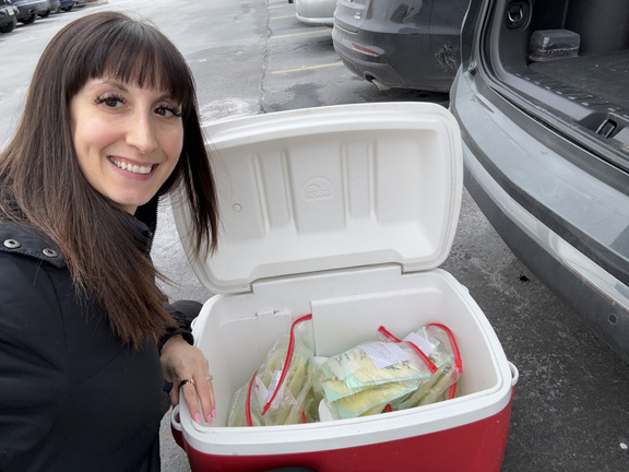 Beth beside a cooler filled with frozen donated milk